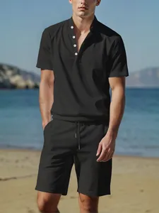 Full view of a man wearing a black linen Henley shirt and shorts on a sunny beach.