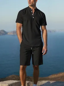 Stylish male model in black cotton linen Henley shirt and shorts set with coastal view.