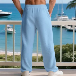Detailed back view of men's blue waffle texture lounge pants in a seaside setting