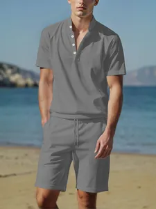 Close-up of a men's grey linen henley shirt and shorts set on a beach background.