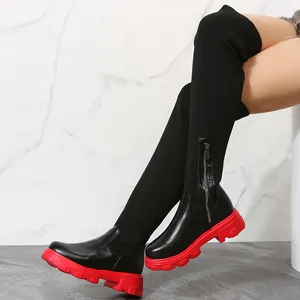 Detail of black over-the-knee boots with leather knit patchwork and red lug sole