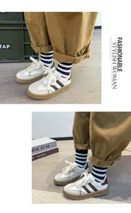 Close-up detail of retro white German Army Trainers with brown stripes and gum sole