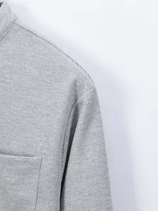 Macro detail of grey waffle knit fabric on men's stand-collar long-sleeve shirt