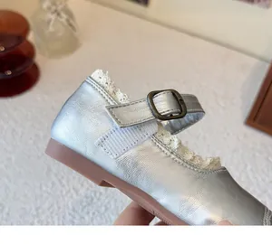 Close-up detail of silver baby girl princess shoes with white lace trim and buckle