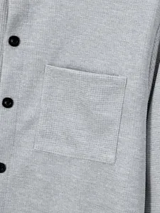 Close-up of grey waffle knit shirt with chest pocket and black buttons detail