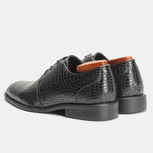 Dettaglio della trama a coccodrillo sulle scarpe eleganti da uomo nere da ufficio.