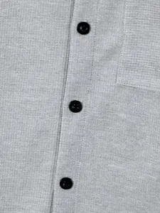 Detailed close-up of grey waffle knit fabric with black buttons on a men's casual shirt