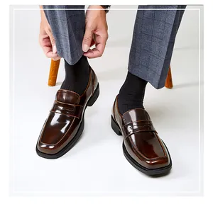 Close-up of men's brown shiny leather square toe loafers worn with grey plaid trousers