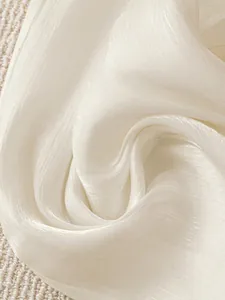 Detailed close-up of white shimmery pleated fabric texture for wide-leg trousers