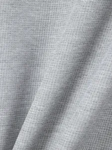 Macro detailed view of the grey waffle knit fabric texture on a men's casual shirt