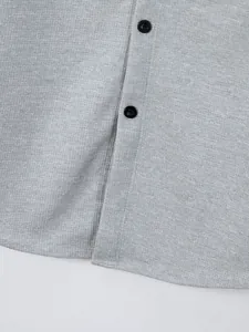 Close-up detail of grey waffle knit men's long sleeve shirt with black buttons
