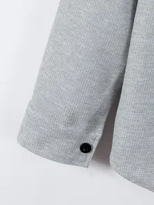Close-up detail of men's grey waffle knit shirt sleeve with a single black button