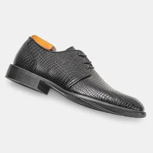 Dettaglio della trama coccodrillo su una scarpa elegante da uomo nera.