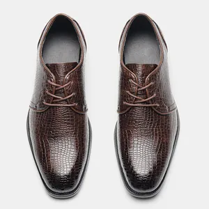 Dettaglio dall'alto delle scarpe da lavoro marroni da uomo con trama in finta pelle coccodrillo