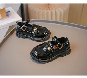 Nahaufnahme schwarzer Lackleder-Loafer für Mädchen mit Blumenverzierung und Gold-Schnalle.