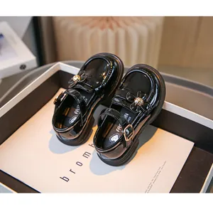 Detailansicht der schwarzen Lackleder-Loafer für Mädchen im britischen Stil mit Blumen-Schnalle