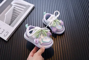 Primer plano de adorables zapatillas para niñas con dijes de tulipán en púrpura y blanco.
