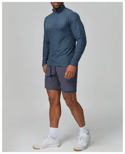 Full body view of men's blue slim fit long sleeve gym shirt and grey shorts.