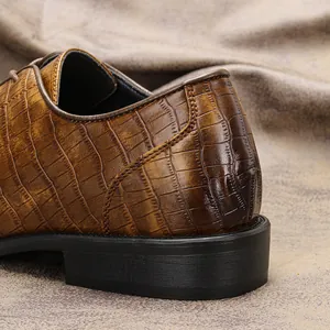 Dettaglio della trama a coccodrillo sul tallone delle scarpe da uomo marroni.