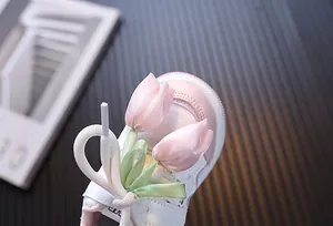 Primer plano de tulipán de satén rosa y lazo en zapatos de suela blanda para niñas