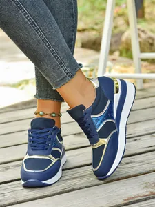 Λεπτομέρεια από μπλε και χρυσά sneakers με χοντρή σόλα, πλέγμα και κορδόνια μπροστά
