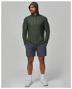 Full body view of a male athlete in a green quick-dry hooded top and active grey shorts