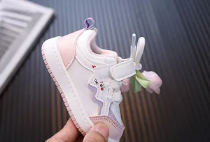 Vista detallada de zapatilla rosa y blanca para niña con motivos de flores y cerezas