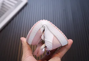 Primer plano que muestra la flexibilidad extrema y la suela blanda del zapato rosa para niña.