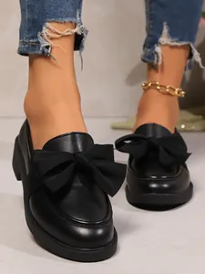 Close-up of black retro loafers with a large decorative bow and chunky sole for women