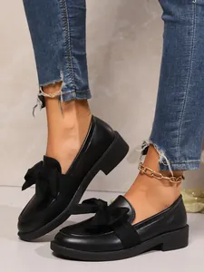 Detailed view of women's black retro loafers featuring a chic bow and thick rubber sole