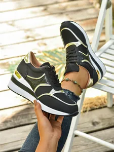Λεπτομέρεια μαύρων sneakers με πλατφόρμα, χρυσές μεταλλικές πινελιές και σχέδιο με κορδόνια