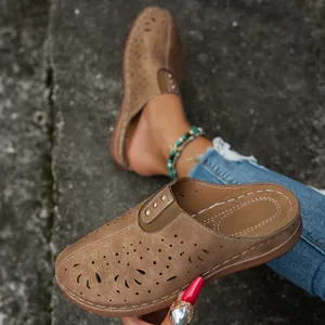 Close-up of brown closed-toe hollow-out mules with metal stud details and comfort sole.