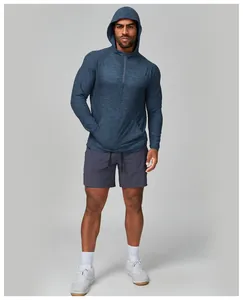 Male model wearing a heathered blue hooded long-sleeve athletic shirt and charcoal shorts