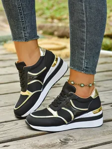 Κοντινό πλάνο μαύρων και χρυσών sneakers με πλατφόρμα σε ξύλινο μονοπάτι