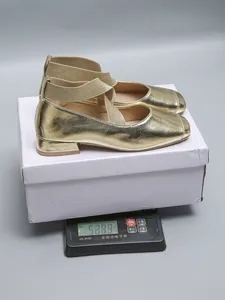 Gold square toe Mary Jane shoes with elastic straps being weighed on a digital scale