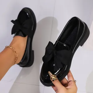 Vintage black patent leather platform loafers featuring oversized bow and chunky heel for women