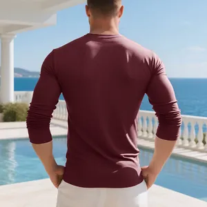 Back view of a burgundy long-sleeved men's cotton t-shirt in a coastal setting
