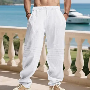 Detailed view of white loose linen trousers for men with drawstring waist and knee pleats