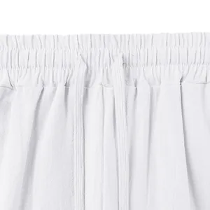 Close-up of white linen men's pants featuring elastic waistband and drawstring detail