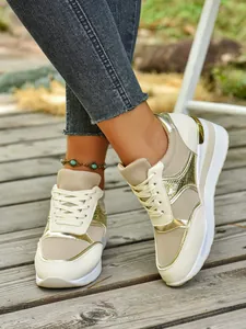 Κοντινό πλάνο κομψών μπεζ γυναικείων sneakers με χρυσές μεταλλικές λεπτομέρειες.