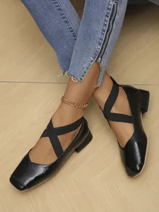 Detailed macro view of black patent leather Mary Jane shoes featuring elastic cross straps
