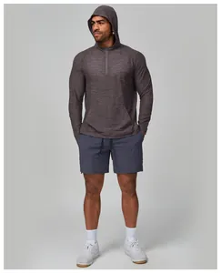 Male model wearing grey long-sleeve hooded fitness top and blue athletic shorts