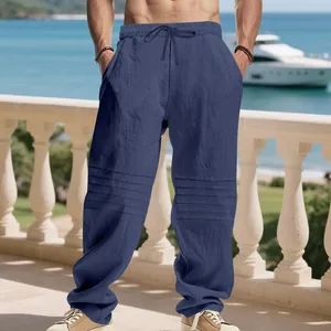 Macro view of men's loose blue linen trousers with unique horizontal pleated knee details.