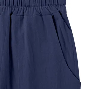 Detail view of navy blue linen trousers showing elastic waist and side pocket.