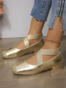 Close-up detail of golden mirror finish Mary Jane flats with elastic cross straps