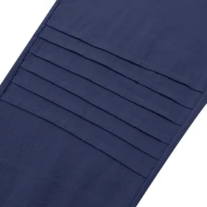 Close-up detail of navy blue linen fabric with decorative horizontal pleats on men's pants