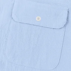 Macro view of light blue linen shirt pocket with white button and stitched detail