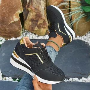 Detailed view of black wedge sneakers with gold accents and a white platform sole.