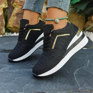 Detailed close-up view of black wedge sneakers with mesh panels and gold metallic accents