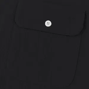 Detailed view of the functional pocket and white button on a black linen shirt
